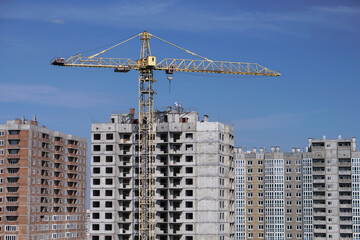 Multi-stage construction during the construction process with a yellow crane. Industrial background for design.