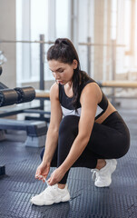 Wall Mural - Fit young girl in sportswear tying shoelaces at health club