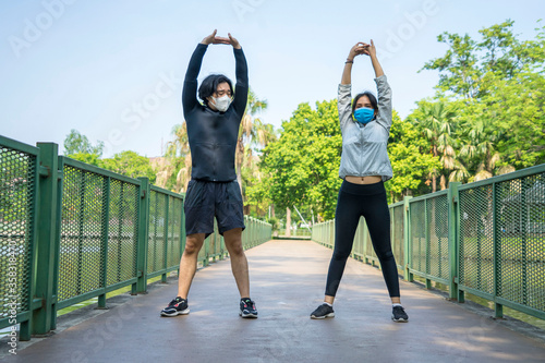 Couples wear sports masks, face masks and come for a morning exercise at the park.Social distancing ,work out and New normal concept