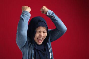 Wall Mural - Portrait of success beautiful muslim businesswoman wearing hijab screaming shouting and shows winning victory gesture