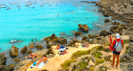 Wall Mural - paradise clear torquoise blue water with boats and cloudy blue sky in background in Favignana island, Cala Rossa Beach, Sicily South Italy.