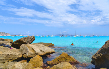 Wall Mural - paradise clear torquoise blue water with boats and cloudy blue sky in background in Favignana island, Cala Rossa Beach, Sicily South Italy.