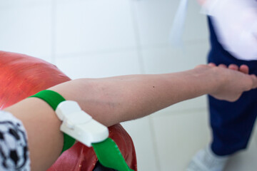 the patient hand is tightened with a medical tourniquet, the nurse is preparing for blood sampling for analysis