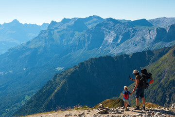 Family summer holidays in mountains. Father and his little son admire and take photo of  Alps mountain landscape. Back view. Active vacation with kid, fathers day concepts. France tourism background.