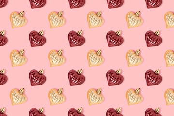 Pattern made of New Year decorations in heart shape on a pink pastel background. Creative festive concept.