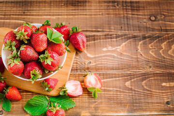 Wall Mural - Ripe sweet strawberries in white plate on the wooden background. Copy space