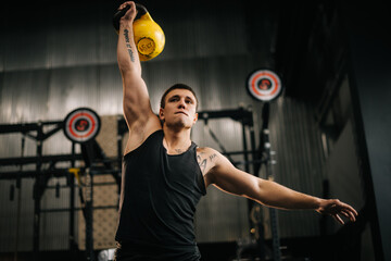 athletic muscular man with perfect beautiful body wearing sportswear lifting heavy free weights over