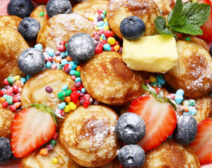 Wall Mural - Little pancakes called poffertjes with strawberries, blueberries and colourful candies. 