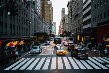 Big city life with crowded street and taxi cars on road controlling by traffic lights in district with modern architecture, taxi cabs and autos stopping on crosswalk near building of downtown district