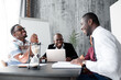 © DmitryStock - A fascinating discussion of black African American colleagues sitting at the office table in the morning meeting.