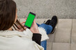 © Ahmed - Young caucasian woman looking at her smartphone in urban background. Brunette girl wearing casual clothes sitting on stairs.