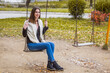 © Ahmed - Young woman is swinging on a swing in autumn park.