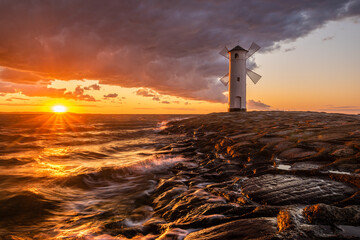 Wall Mural - lighthouse in the shape of a windmill in swinoujscie in poland during the dramatic sunset.