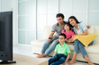 © ake1150 - Asian happy family with father, mother, son and daughter sitting in sofa and watching television at home concept of family values, vacation day, holiday, happiness or lifestyle.