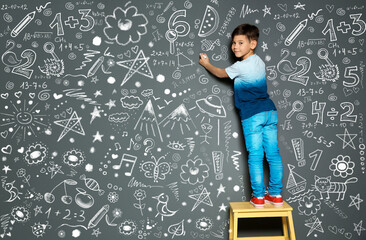 Little child drawing with chalk on gray wall