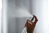 Fototapeta  - Woman spraying air freshener indoors closeup. Space for text