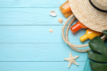 Sun protection products and beach accessories on light blue wooden background, flat lay. Space for text