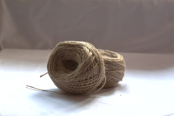 Closeup of two balls of jute twine on white table, gray background, copy space