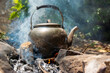 An ancient and antique teapot boiling over a fire flame