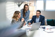© sibstock - In Creative Office Productive Coworkers Standing at the Table, Company Meeting. Colleagues and clients talking strategy with laptop and tablet.