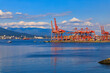 Vancouver harbour with red gantry cranes and cargo shipping containers at the Centerm terminal on the waterfront, Canada