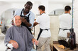 © JackF - African hairdresser doing styling for gray-haired man