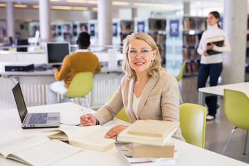 Wall Mural - Portrait of successful teacher woman with book in public library