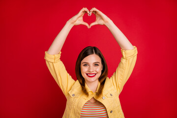 Poster - Photo of attractive lady good mood hold arms together above head making fingers heart figure express cardiac feelings wear casual yellow blazer jacket isolated vivid red color background