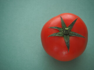 tomato close-up, one red tomato, green background