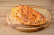 © zhinna - Calzone, Italian traditional food. Served on wooden board over rustic wooden table background closeup.