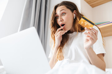 Poster - Portrait of excited woman and holding credit card while using laptop