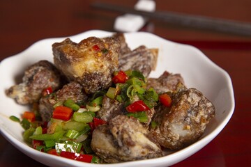 Wall Mural - Closeup shot of a plate of ribs with vegetables and spices on a wooden table