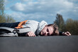 © Евгений Шемякин - Young unconscious dead man at accident scene, crash on the road. Pedestrian guy, teenager hit by a car on the road while crossing highway. Downed male person is lying on asphalt. Dangerous situation