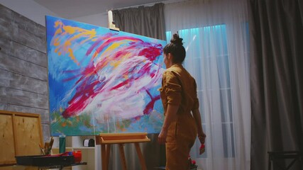 Wall Mural - Young artist looking at her colorful abstract painting. Modern artwork paint on canvas, creative, contemporary and successful fine art artist drawing masterpiece