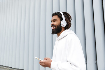 Wall Mural - Smiling young man listening music by headphones