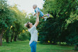 © y_free_art - Happy mother playing with her little child on nature background in summer day. Mother having fun with her baby daughter outdoors, throws her up into the air and catching back. Happy motherhood.