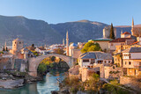 Fototapeta  - Skyline of Mostar with the Mostar Bridge, houses and minarets, at the sunset in Bosnia and Herzegovina