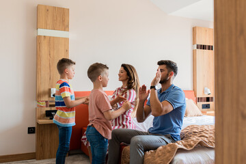 Wall Mural - family of four having fun and enjoying together at hotel room.