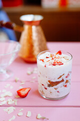 Wall Mural - layered summer dessert with strawberries, sponge cake and yogurt on a pink tree background.