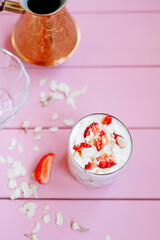 Wall Mural - layered summer dessert with strawberries, sponge cake and yogurt on a pink tree background.