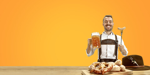 Delighted man with beer dressed in traditional Austrian or Bavarian costume holding mug of beer at pub or studio. The celebration, oktoberfest, festival, drinking concept. Flyer with copyspace.