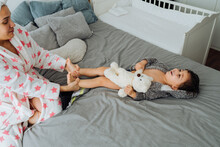 From Above Of Content Woman In Bathrobe Having Fun With Little Boy On Soft Bed