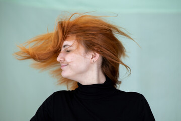 Wall Mural - Close up portrait of pretty redhead girl with long wavy hair blowing on the wind.