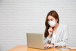 © comzeal - Young Asian woman using laptop and wearing face mask