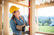 © leszekglasner - Woman worker at building site of wood frame house using level tools