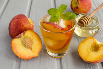 Wall Mural - Cold tea with peaches in the glass on the grey wooden background