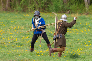 Knights in armor fight on the battlefield. Reconstruction of an ancient battle of the 15th century.