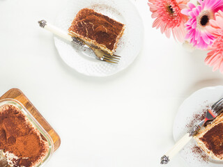 Traditional coffee tiramisu dessert with mascarpone cheese and cocoa powder served on plates on white wooden table