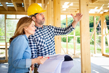 Architect or engineer with blueprints meeting with owner of building house on construction site