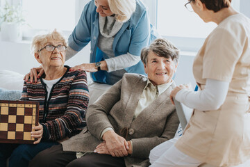 Wall Mural - Older ladies sit on a couch and talk to a nurse at a local nursing home